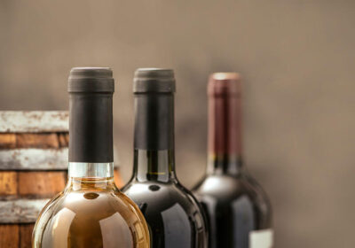 Bottles of white and red wine displayed against a rustic wooden barrel background, highlighting wine culture and enjoyment.