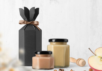 Black gift box with ribbon, two jars of honey, honey dipper, and apple slices, emphasizing hobbies related to natural products and DIY crafts.